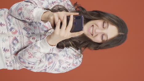 Vertical-video-of-Happy-young-woman-texting-on-the-phone.-Smiling.